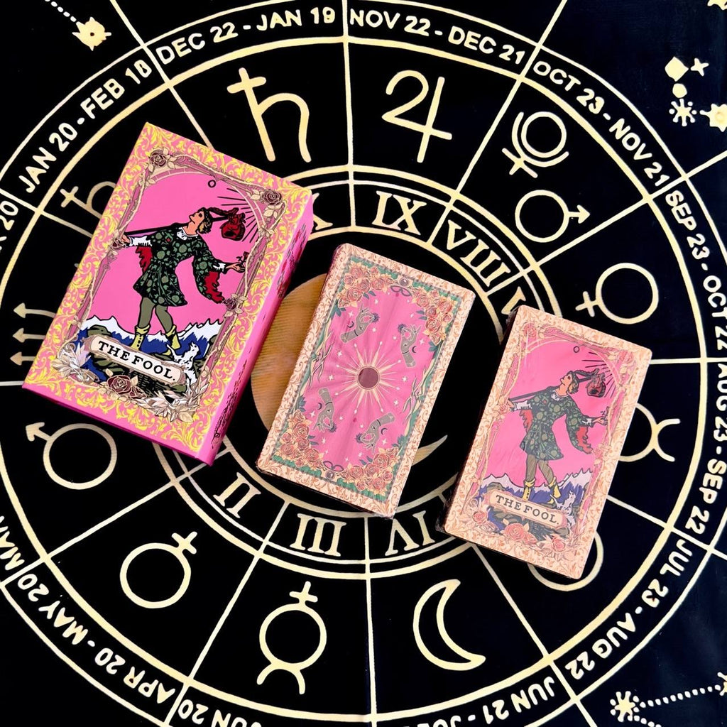 Pink foil tarot cards with 'The Fool' card on a black astrological wheel background