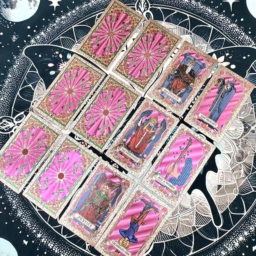 Set of rose gold foil tarot cards with pink backgrounds and detailed artwork on a starry night design background.
