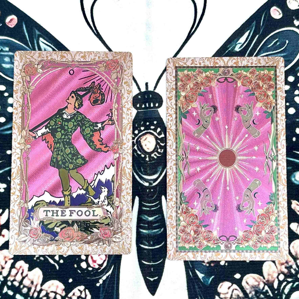 Two foil tarot cards featuring 'The Fool' and another card with a central figure on a decorative background.