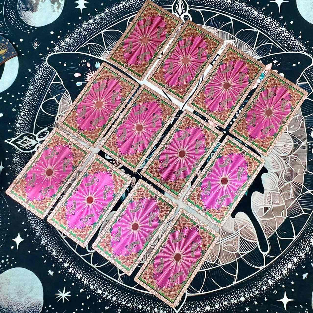 Nine pink foil tarot cards arranged in a circular pattern with celestial design elements.
