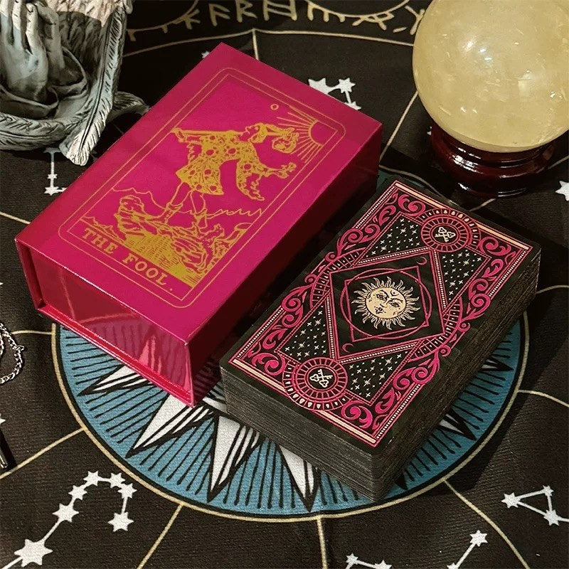Solis & Luna gold foil cards with a red box featuring a tarot card design on a astrological-themed surface.