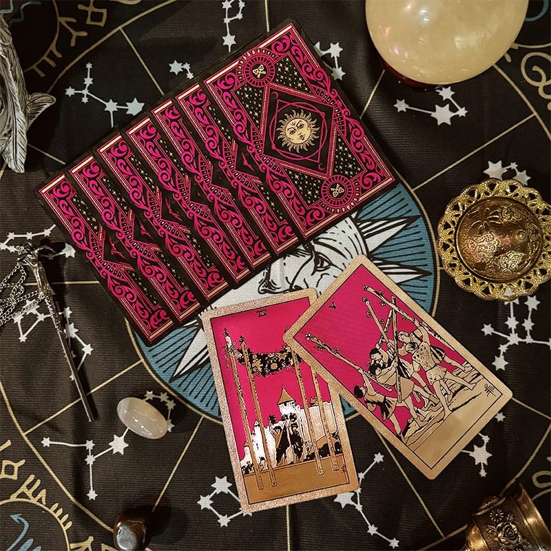 Set of Gold Foil tarot cards on a dark surface with star constellations and celestial decorations.