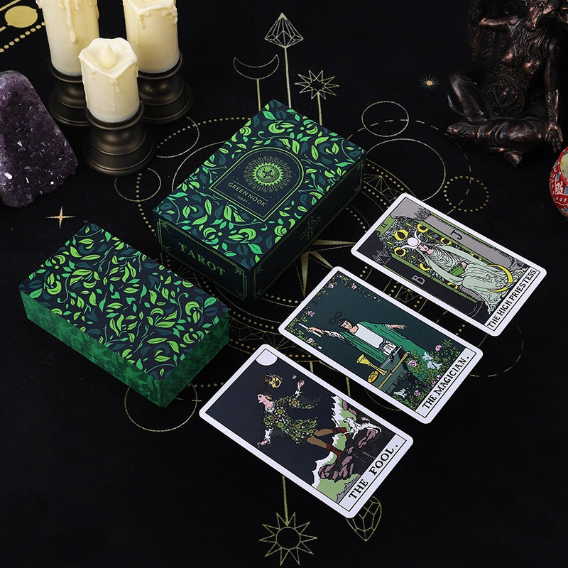 Green tarot cards with intricate designs on a dark surface with candles and crystals.