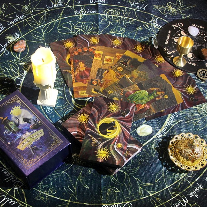 witch gold foil Tarot cards on a mystical tablecloth with candles and other paraphernalia